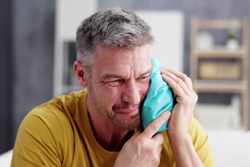 Upset,Man,Touching,Cheek,With,Cold,Water,Bag,At,Home
