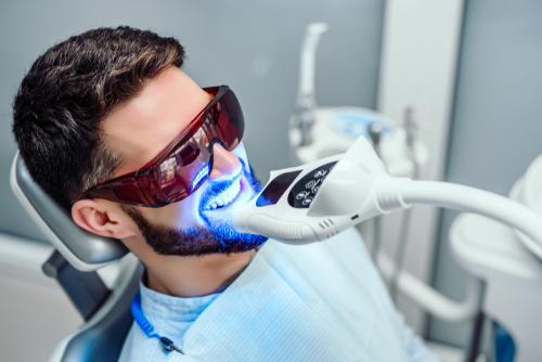 Dentist,Starting,Teeth,Whitening,Procedure,With,Young,Man.